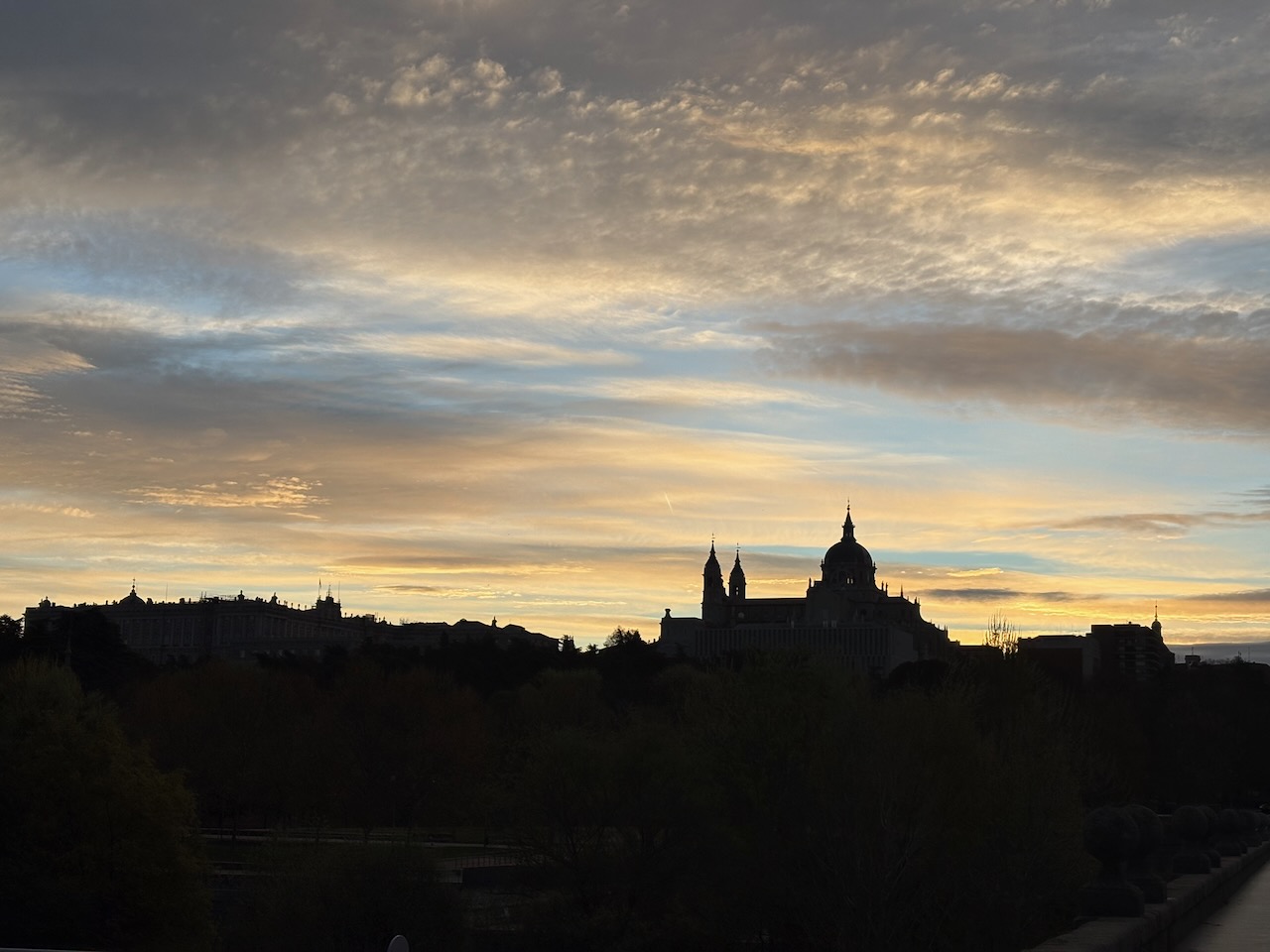 Silhouetted buildings against a colorful sunset sky with scattered clouds.